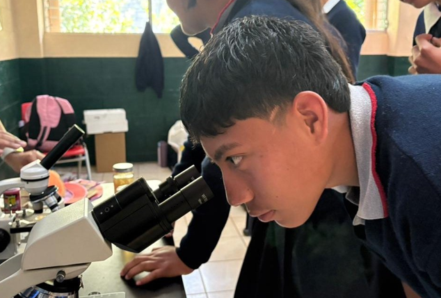 Estudiante observa una muestra a través de un microscopio.
