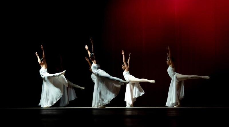 Bailarinas presentan una obra en un escenario iluminado.