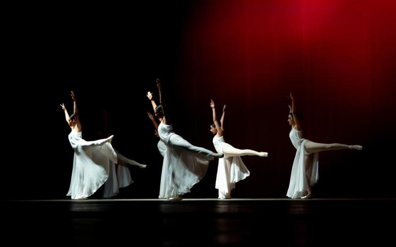 Bailarinas presentan una obra en un escenario iluminado.