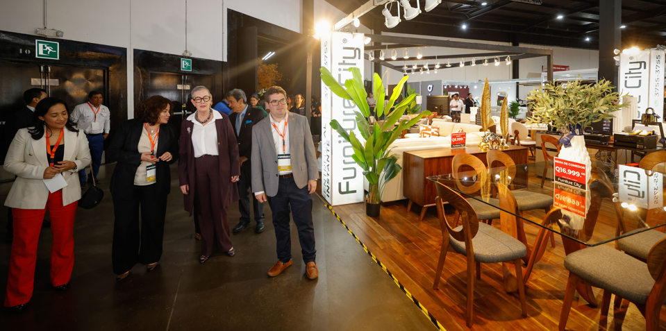 Participantes recorren una exposición de muebles y productos de madera.